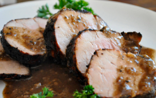 a plate of sliced pok loin covered in gravy