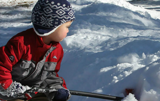 a young boy shoveling heavy snow