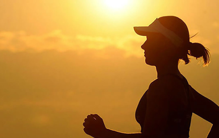 silhouette of a woman running with the sun setting behind her