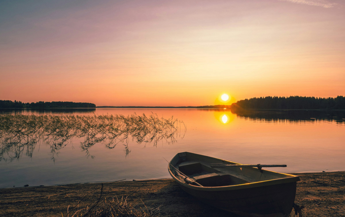 a boat on the edge of the water watching the sunset