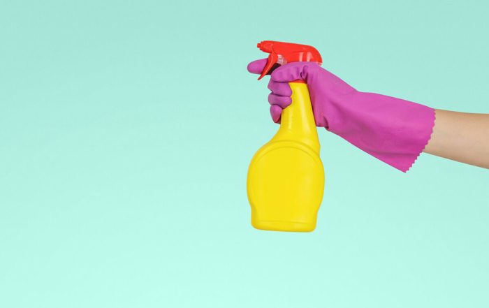 a purple glove holding a yellow spray bottle