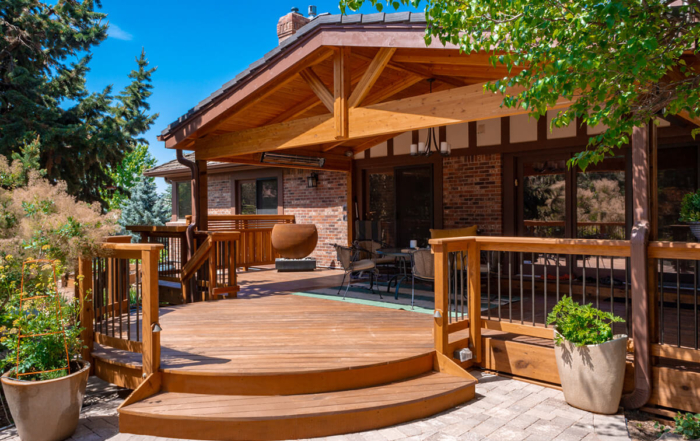 a paver patio leading into a custom wood deck with a roof cover