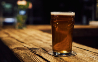 a lonely beer on a dark bar