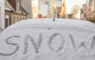 a car covered in snow with snow written on it's window