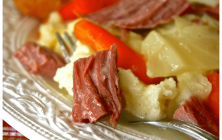 a plate of corned beef, potatoes, and carrots