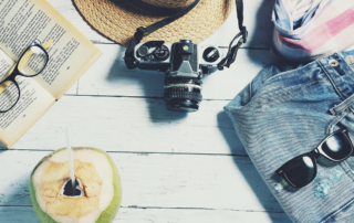 glasses on a book with a camera, hat, shorts, and sunglasses