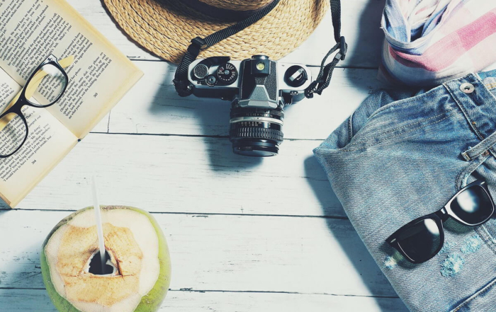 glasses on a book with a camera, hat, shorts, and sunglasses