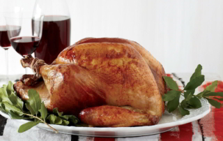 a beer-brined turkey on a platter with wine in the back