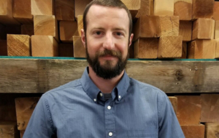 contractor standing in front of wood stack