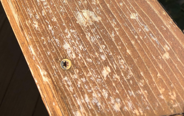 a closeup picture of a deck board with hail damage