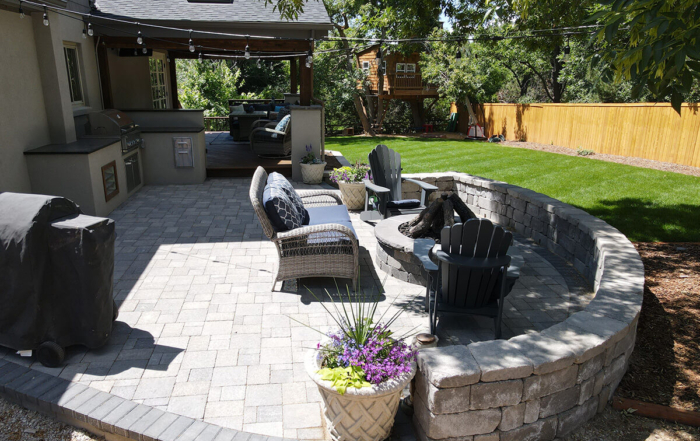 Paver patio with stone wall connected to a wood deck