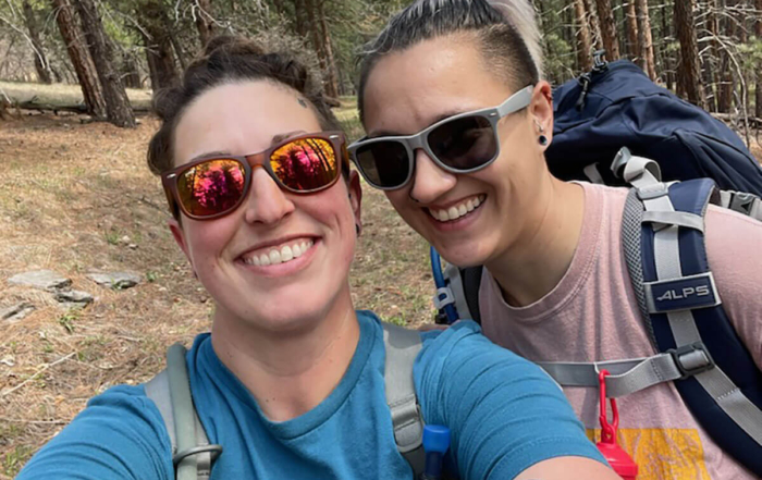 2 women with sunglasses smiling on a hike