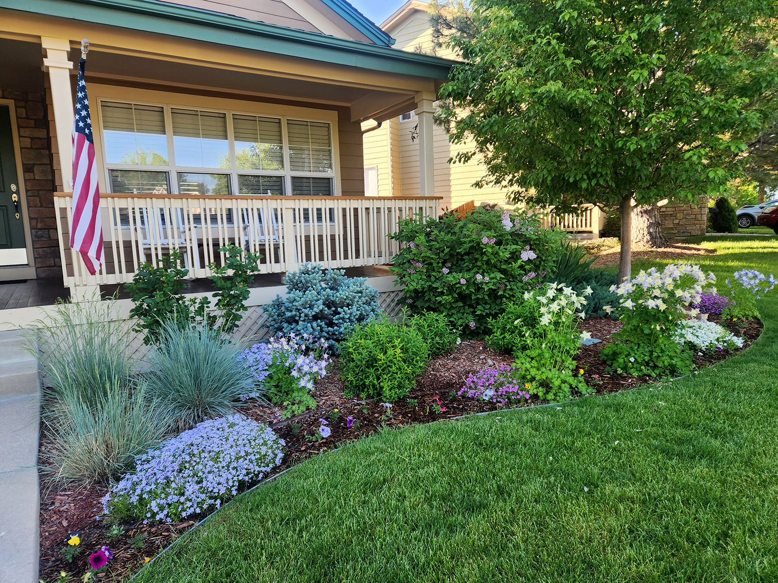 beautiful landscaping in front of wood deck