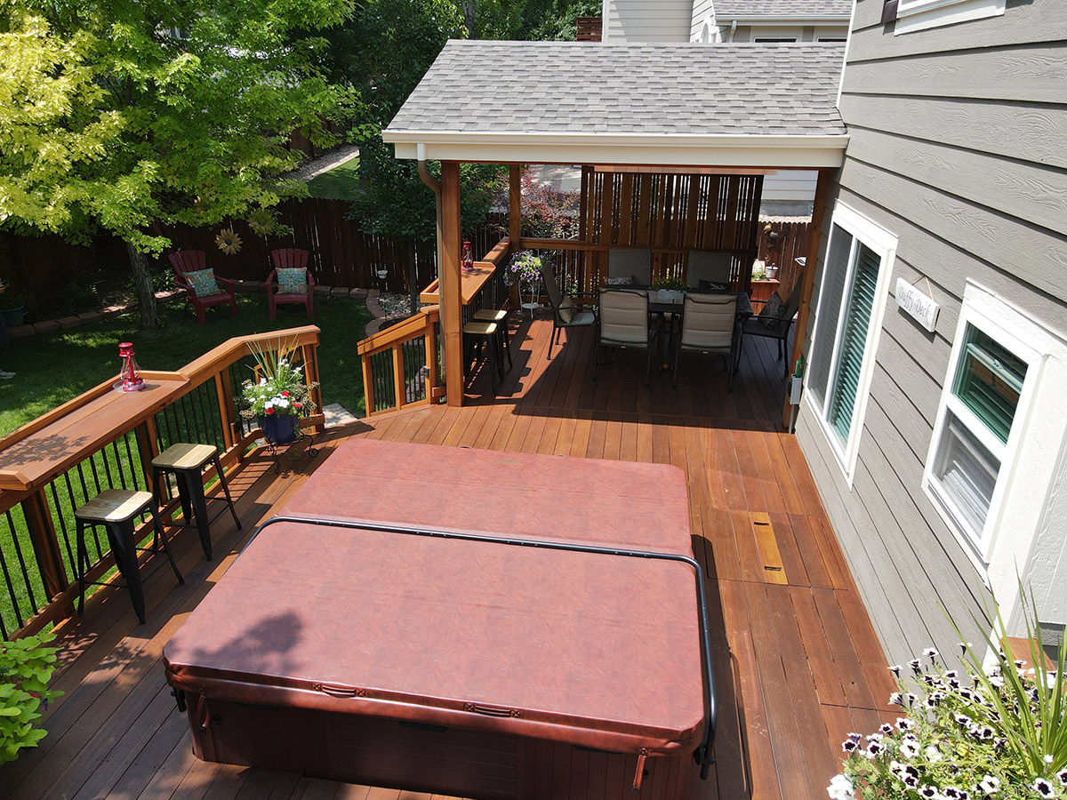 custom wood deck with a roof cover and spa